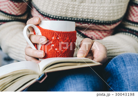 Red Knitted woolen cup in female hands. Red Knitted woolen cup in female hands. 30043198