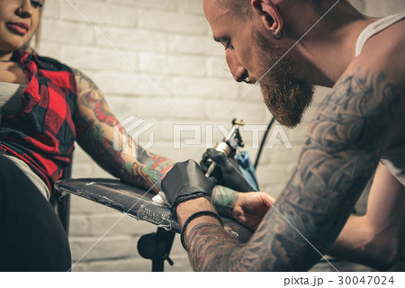 Calm male creating picture on female arm Calm male creating picture on female arm 30047024