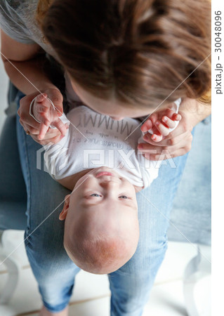 Newborn child lies on his mother's lap 30048096