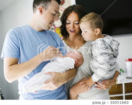 Mother and father carrying son (4-5) and daughter (0-1 months) 30051660