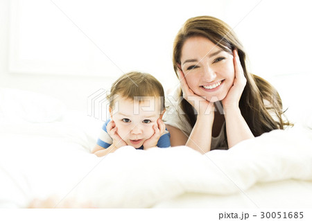 Mother and son (4-5) lying on bed  and smiling 30051685