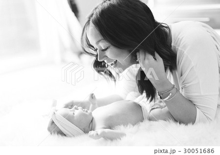Mother playing with daughter (0-1 months) on bed 30051686