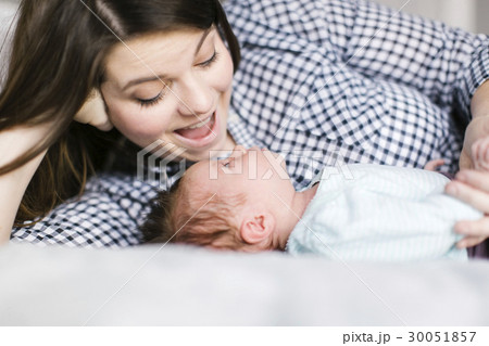 Young mother with baby girl (0-1 months) lying on bed 30051857
