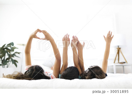 Brothers ( 6-7, 8-9 ) and sister ( 10-11 ) lying on bed and gesturing 30051895