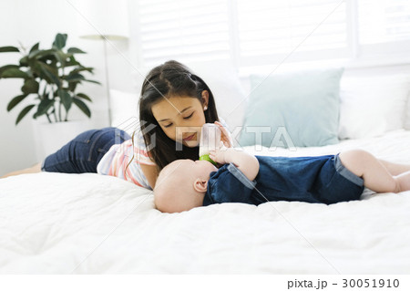 Sister ( 10-11 ) feeding brother ( 2-5 months ) with baby bottle 30051910