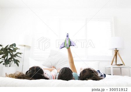 Brothers ( 6-7, 8-9 ) and sister ( 10-11 ) lying on bed and playing with toy 30051912