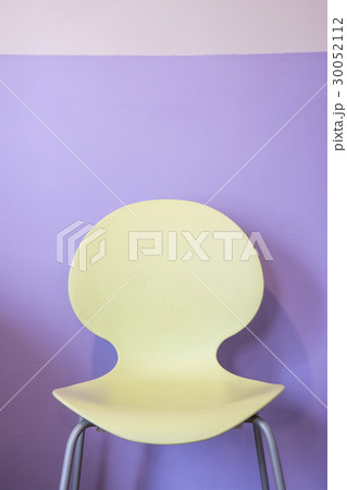 Empty yellow chair by purple wall 30052112