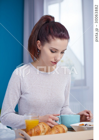 Attractive woman eating cereals sitting on bed at home Attractive woman eating cereals sitting on bed at home 30063882