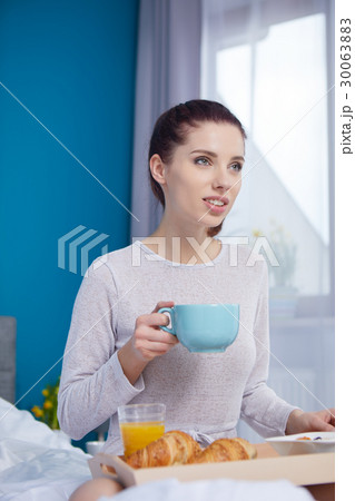 Attractive woman eating cereals sitting on bed at home Attractive woman eating cereals sitting on bed at home 30063883