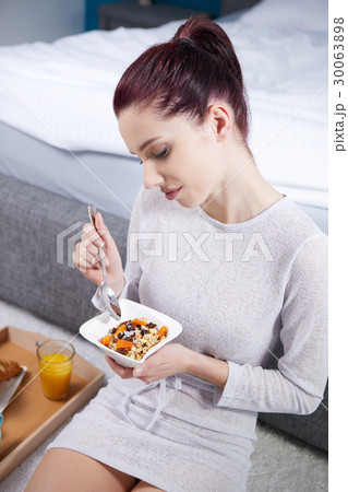 Attractive woman eating cereals sitting on bed at home 30063898