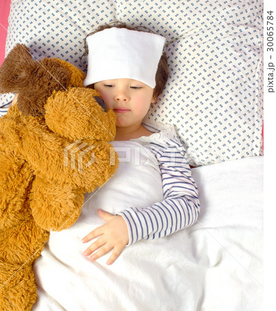 little girl with a headache in bed with teddy bear 30065784