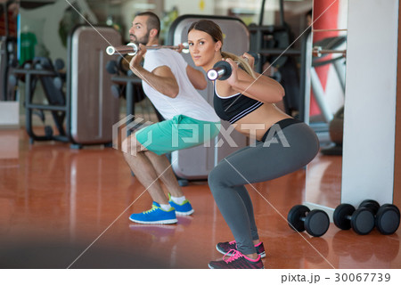 young man and woman with barbell flexing muscles young man and woman with barbell flexing muscles 30067739