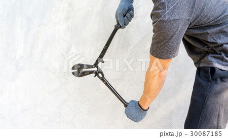 Man wear a glove and holding cutting pliers on gray background. 30087185