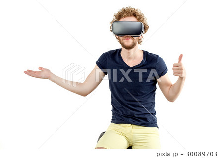 Young curly-haired man using a VR headset and 30089703