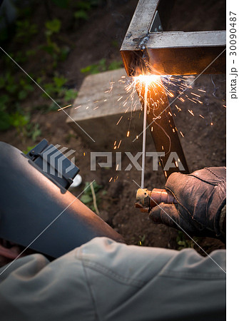 Worker in mask welding steel railings outdoors 30090487