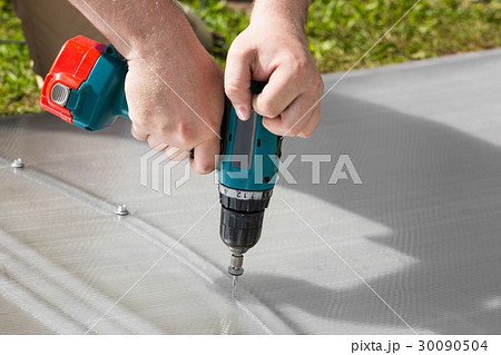Worker screwing screw into polycarbonate 30090504