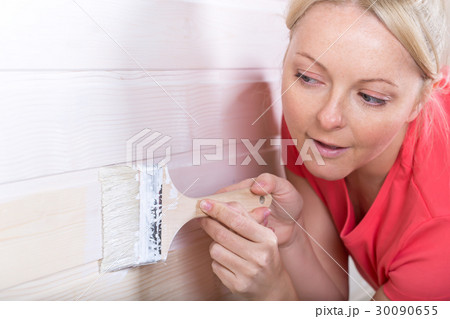 Woman painting wooden boards in white color 30090655
