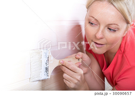 Woman painting wooden boards in white color 30090657