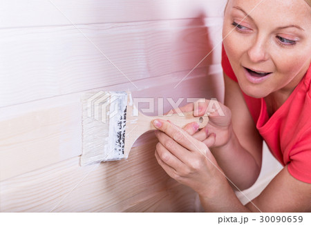 Woman painting wooden boards in white color 30090659