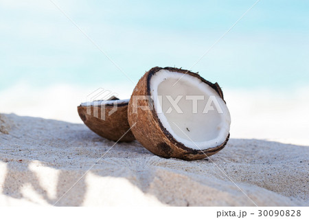 Broken brown coconut on sandy beach Broken brown coconut on sandy beach 30090828