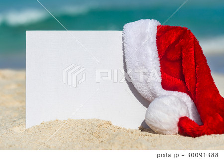 Santa Claus Hat and blank placard on sandy beach Santa Claus Hat and blank placard on sandy beach 30091388