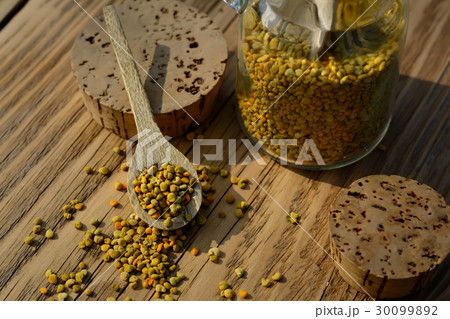 Grains of bee pollen in jar and wooden spoon on 30099892