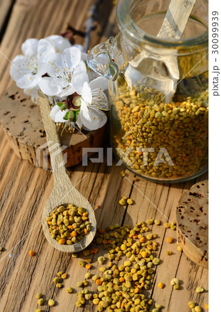 Grains of bee pollen in jar and wooden spoon on 30099939