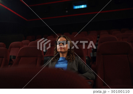 Young woman watches movie 3D at the cinema and drinks coffee, lo 30100110