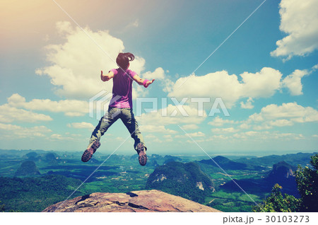 cheering oung woman jumping on mountain peak 30103273