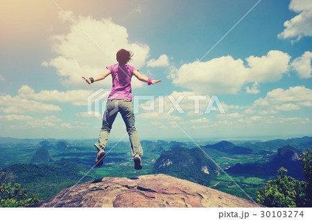 cheering oung woman jumping on mountain peak 30103274