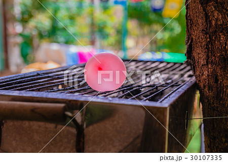 Balloon filled with water placed on a hot grill 30107335