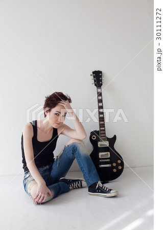 the girl with the guitar sits on the floor 30111272