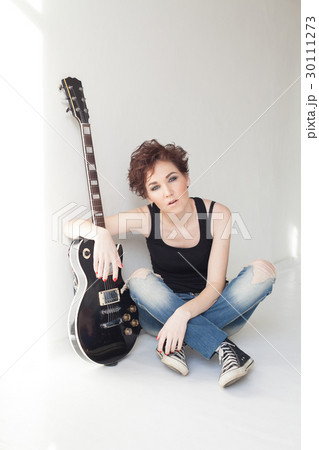 the girl with the guitar sits on the floor 30111273
