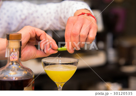 Barman putting lemon peel to prepare coctail 30120535