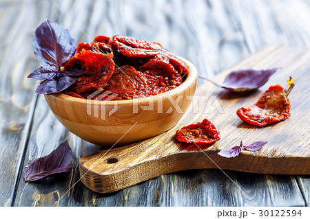Bowl with sun-dried tomatoes and wooden board. 30122594