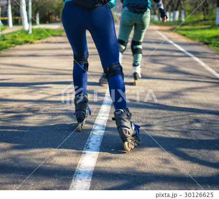 Two girls on roller skates ride along the road 30126625