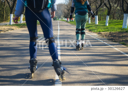 Two girls on roller skates ride along the road 30126627