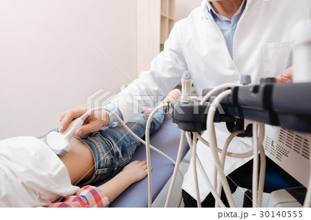 Competent sonographer examining patient abdomen in 30140555