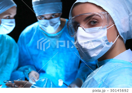 Three surgeons at work operating in surgical 30145692
