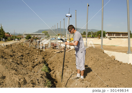 Geodesist measures at a countryside stadium Geodesist measures at a countryside stadium 30149634