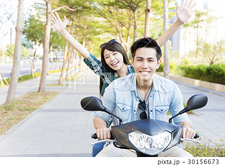 happy young couple riding scooter in town happy young couple riding scooter in town 30156673