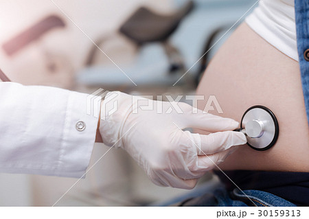 Qualified practitioner examining pregnant abdomen 30159313