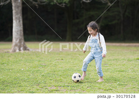 サッカーボールで遊ぶ裸足の女の子の写真素材