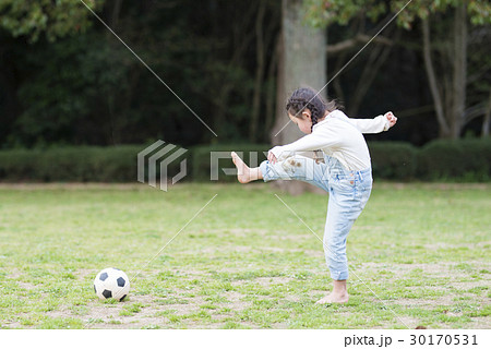 サッカーボールで遊ぶ裸足の女の子の写真素材