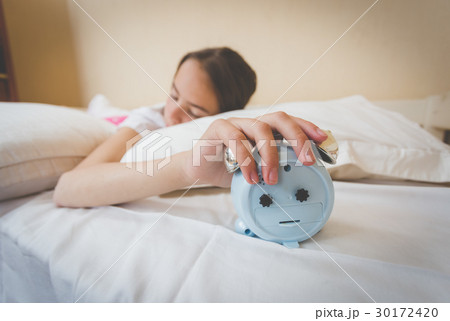 Closeup photo of woman turning off alarm clock 30172420