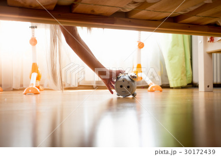 Young woman reaching under bed for alarm clock 30172439