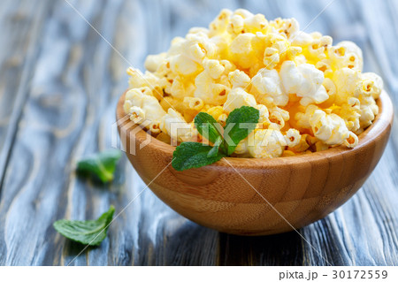 Crispy popcorn with salt in a wooden bowl closeup. 30172559