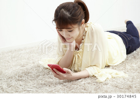 床に寝そべってスマホを触る若い女性 30174845