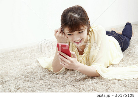 床に寝そべってスマホを触る若い女性 30175109