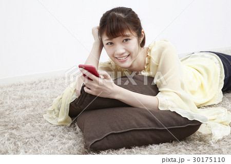 床に寝そべってスマホを触る若い女性 30175110